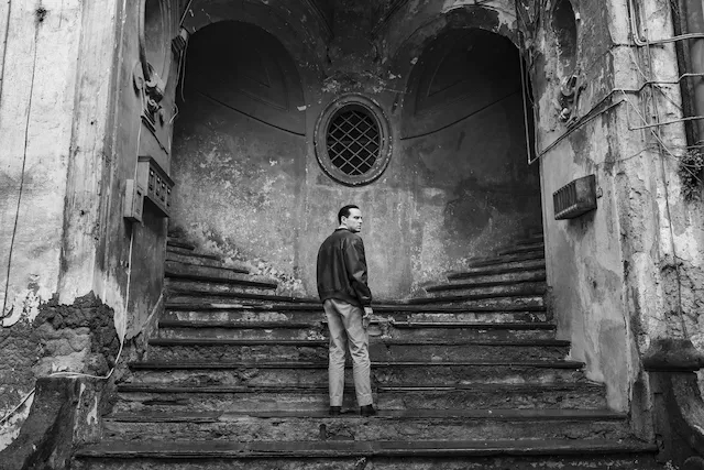 Still from the series Ripley featuring Andrew Scott as Tom Ripley on a staircase that splits.